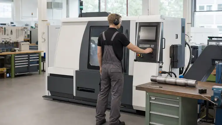 CNC-Zerspanungshalle mit Metallwerkstück und Spänen im Fokus